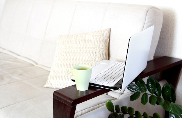 A laptop and a cup of tea on the sofa. Home Office.