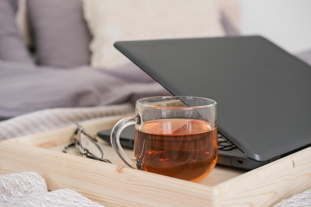 Laptop and cup of tea on a tray on the bed in the bedroom Work from home distance learning