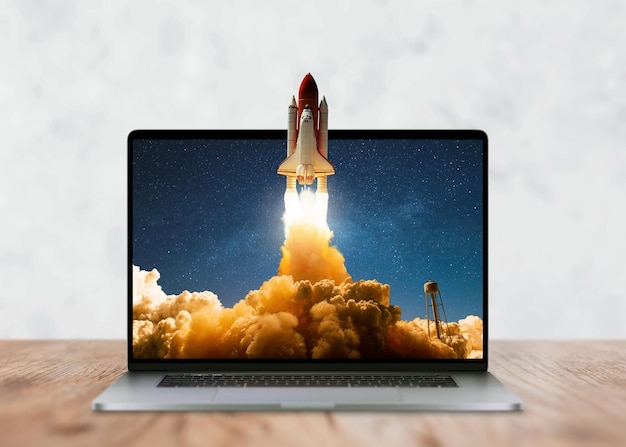 laptop on the desktop and the space shuttle rocket successfully takes off beyond the frames of display start up and success creative idea development marketing and application concept