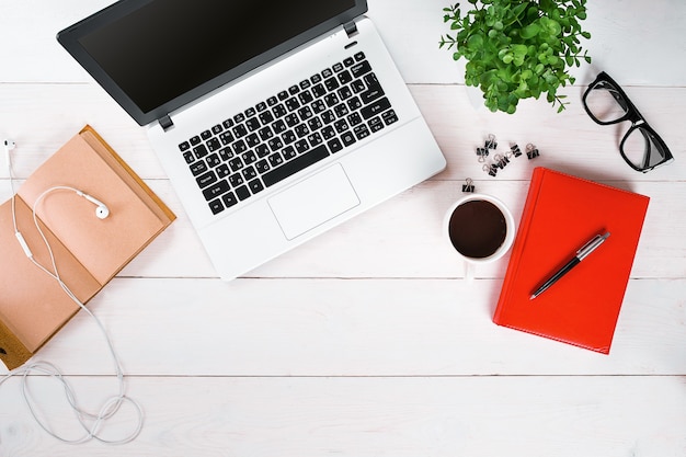 Laptop digital tablet diary coffee cup and potted plant on work desk