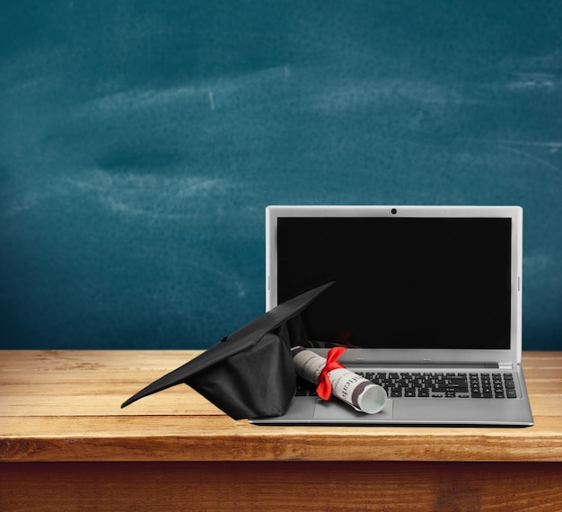 Laptop and diploma scroll on background