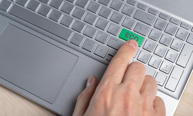Ноутбук и концепция экологически чистых технологий вручную нажимают зеленую кнопку на компьютере