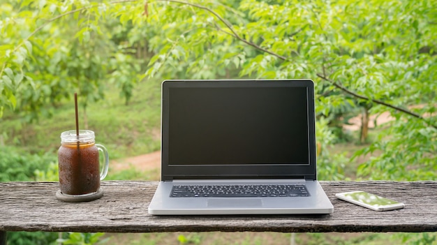 Laptop en bevroren americanokoffie op een houten lijst.