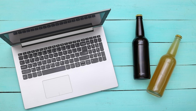 Laptop en flessen bier op een blauwe houten achtergrond. Bovenaanzicht