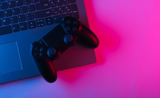 Laptop en gamepads met blauw roze neon levendig licht.