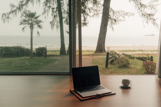 Laptop en hete koffiekop bij deurstap met de mening van het de herfststrand.