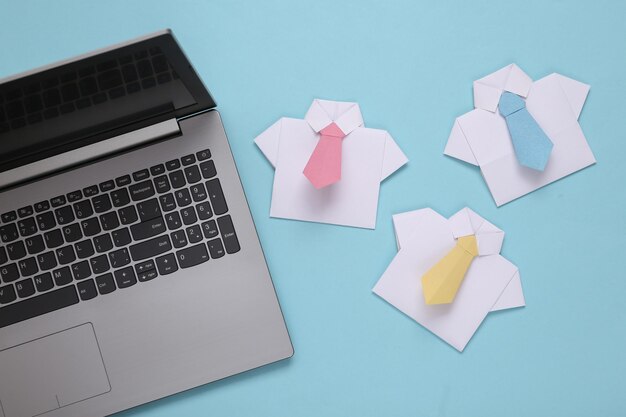 Laptop en Origami shirts met stropdassen op een blauwe pastel achtergrond Leiderschap teamwork bedrijfsconcept