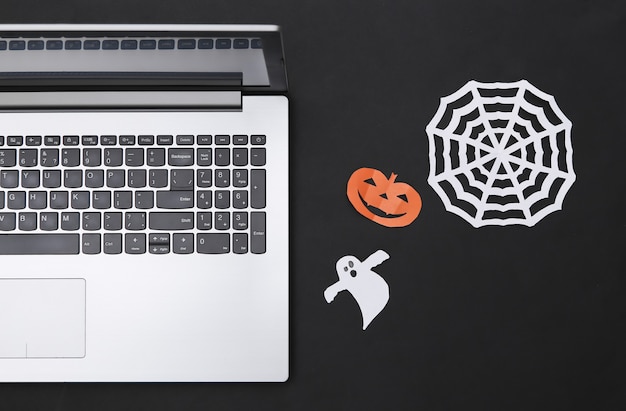 Laptop en papier gesneden Halloween decor op zwarte achtergrond. Bovenaanzicht. plat leggen