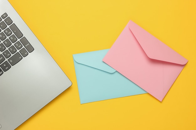 Photo laptop and envelopes on yellow background. valentine's day. top view