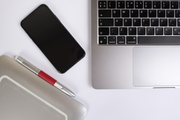 laptop graphics tablet and phone on white table