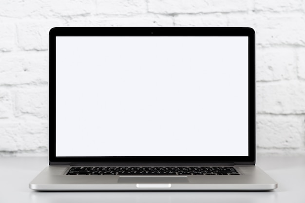 Laptop on grey office table on brick wall background. Mockup with copy space