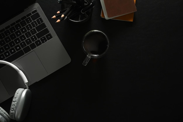 Foto cancelleria per cuffie per laptop e tazza da caffè su pelle nera disposizione piatta e vista dall'alto