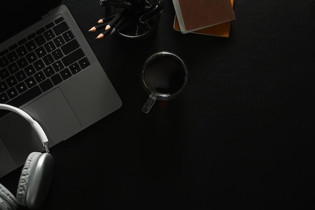 Laptop headphone stationery and coffee cup on black leather Flat lay and top view