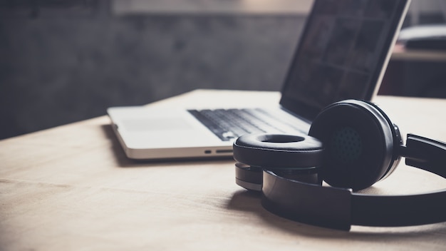 Photo laptop and headphone on wooden table at home.