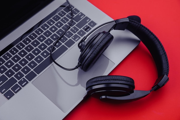 Laptop and headphones on a red background.