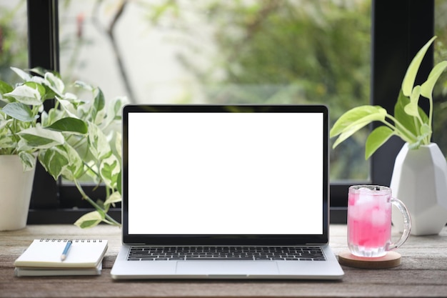 Laptop and Ice Strawberry juice and notebooks and plants on wooden table in front of window