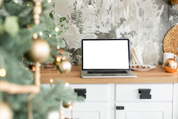 Laptop. kerstboom en geschenken op de achtergrond.