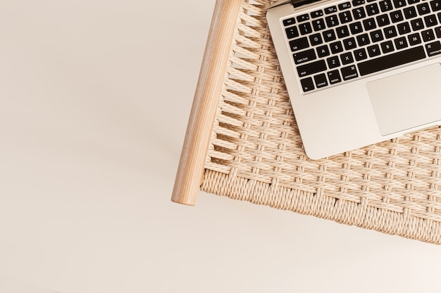 Laptop keyboard and wicker bench on white