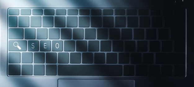 Laptop keyboard with blue light and SEO text on buttons. SEO Search Engine Optimization concept.