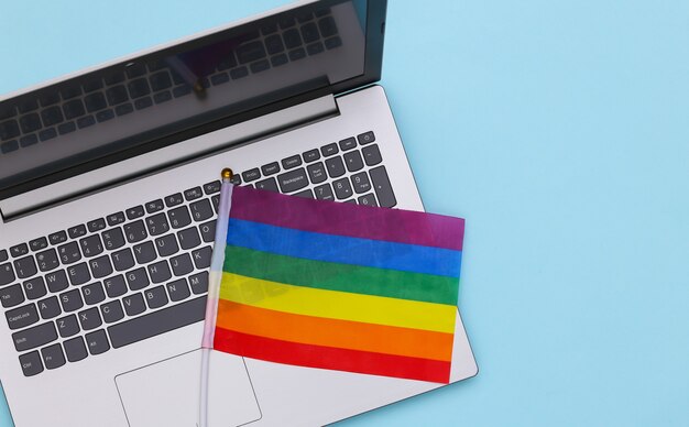 Laptop e bandiera arcobaleno lgbt su sfondo blu. parata gay, libertà, tolleranza