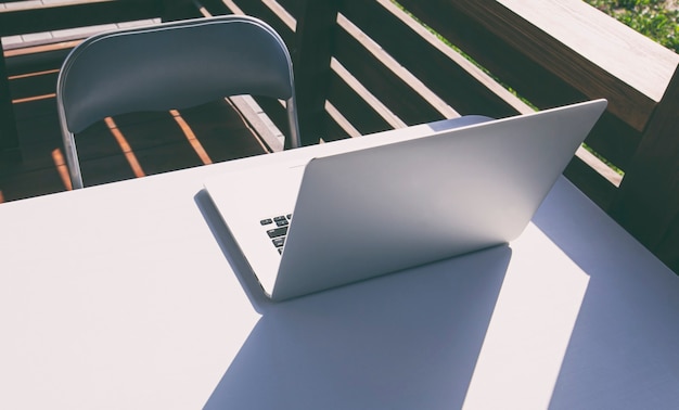 야외 흰색 테이블에 누워 있는 노트북과 햇빛은 흥미로운 그림자를 만듭니다