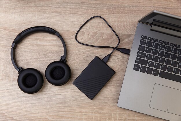 Foto laptop met externe harde schijf en koptelefoon op een houten tafel