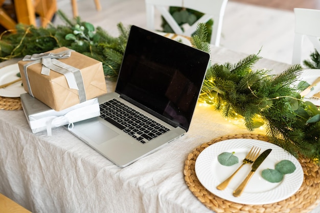 Laptop met geschenkdoos en kerstverlichting achtergrond.