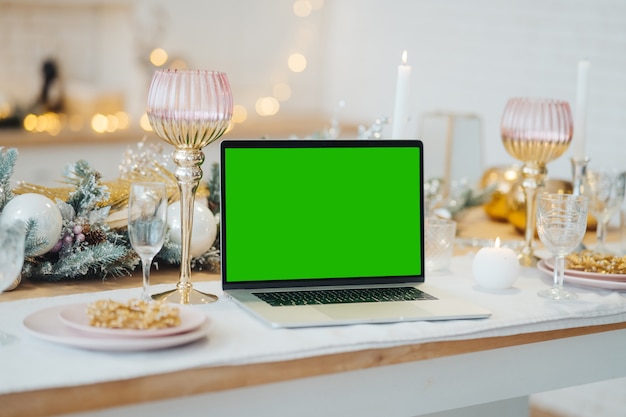 Laptop met groen scherm - chromakey in de buurt van New Year's decoraties. kerstthema. sjabloon.