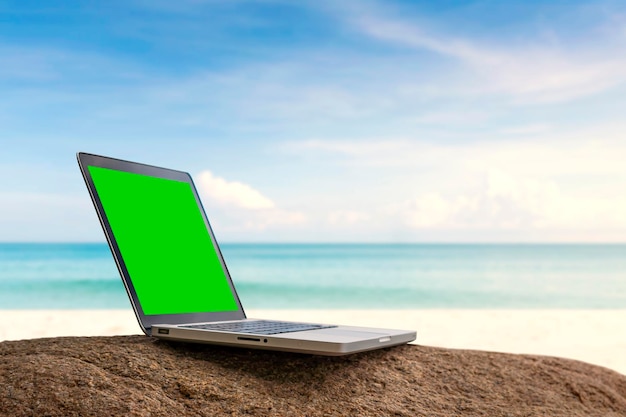 Laptop met groen schermachtergrond op het strand.