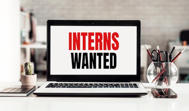 Laptop met INTERNS WANTED tekst op moderne kantoor achtergrond