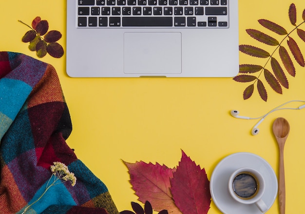 Laptop met koffie, herbarium en deken op gele achtergrond