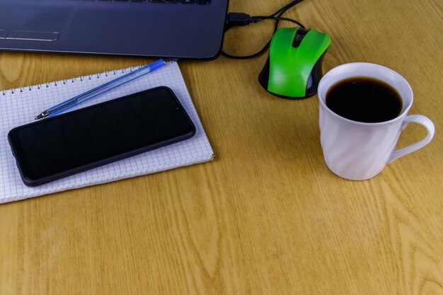 Laptop met muis smartphone notebook pen en kopje koffie op een bureau Thuis werken en bedrijfsconcept