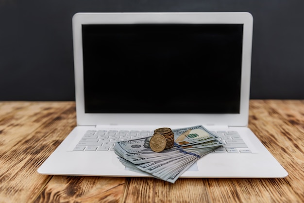 Foto laptop met stapel dollars en gouden munten