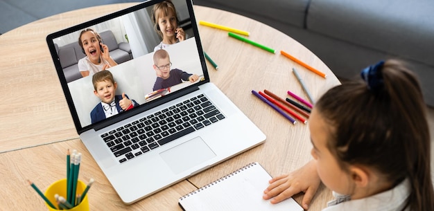 Foto laptop met videoconferentie kinderen klasgenoten staat op tafel.