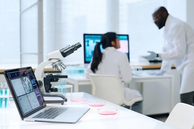 Microscopio portatile e gruppo di piastre di petri in piedi sul posto di lavoro del chimico