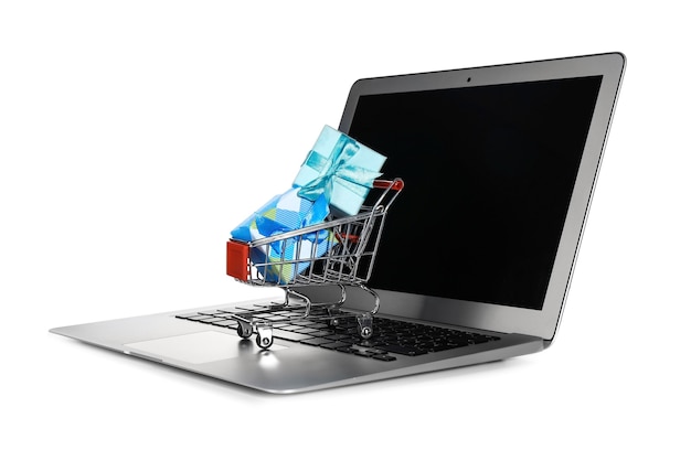 laptop and mini market trolley with gifts, isolated on white. internet shopping concept