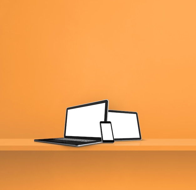 Photo laptop mobile phone and digital tablet pc on orange wall shelf square background