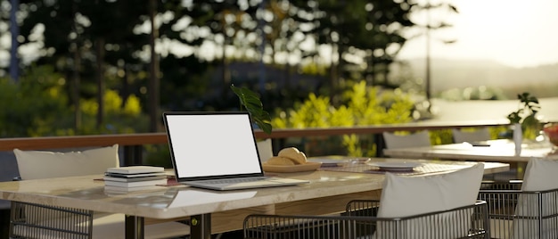 Laptop mockup on beautiful outdoor dining table with beautiful nature view restaurant