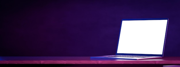 Laptop mockup tafel donkerblauwe muur Zijaanzicht open moderne laptop mockup Laptop leeg wit scherm mockup op houten tafel Mockup in kleurrijke felle neon UV blauwe en paarse lichten 3D-rendering