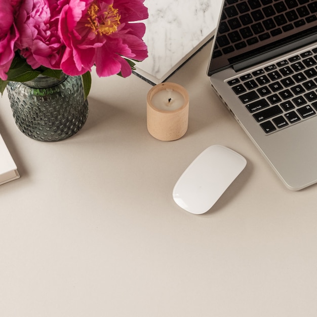 Laptop, mooie roze pioenroos tulp bloemen boeket op tafel. Minimaal bureau aan huis.