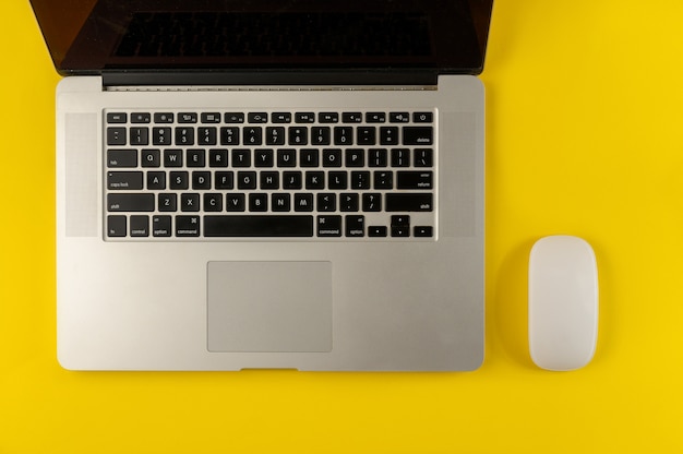 Laptop and mouse isolated on yellow