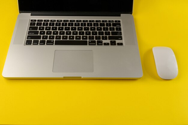 Laptop and mouse isolated on yellow