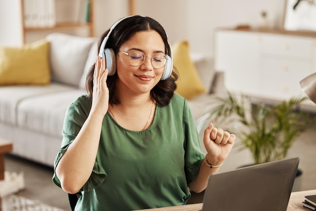 Foto laptop musica e streaming con una donna a casa sua ascoltando la radio nel soggiorno per rilassarsi computer audio e cuffie con una giovane studentessa a casa sua per l'istruzione