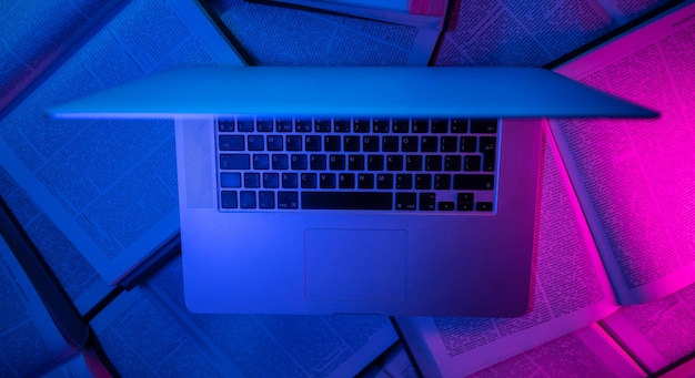 Laptop in neon light on books