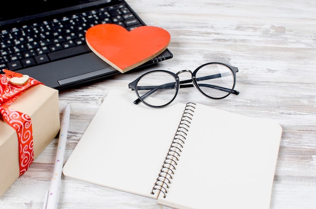 Laptop, notebook en cadeau met hart op houten tafel