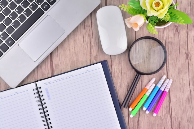 Laptop, notebook with magnifying glass on wooden table