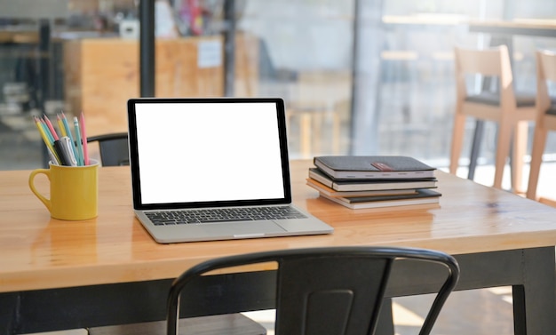 편안한 작업 공간의 테이블 위에 문구류가있는 노트북과 노트북이 놓여 있습니다.