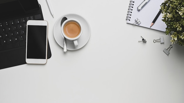 Laptop, notebooks and coffee cup with smartphone on office desk.