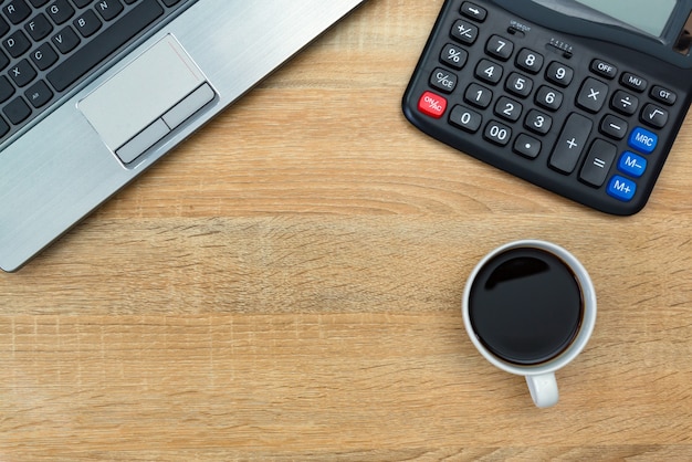 Laptop of notebook, rekenmachine en kopje koffie op tafel