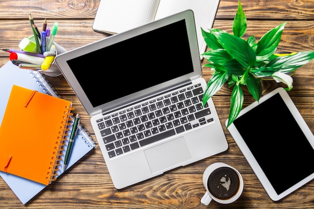 Ноутбук, канцелярские товары и цифровой планшет на деревянном фоне